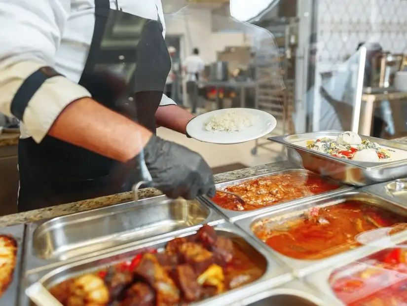 Chef serving rice and dishes from a buffet