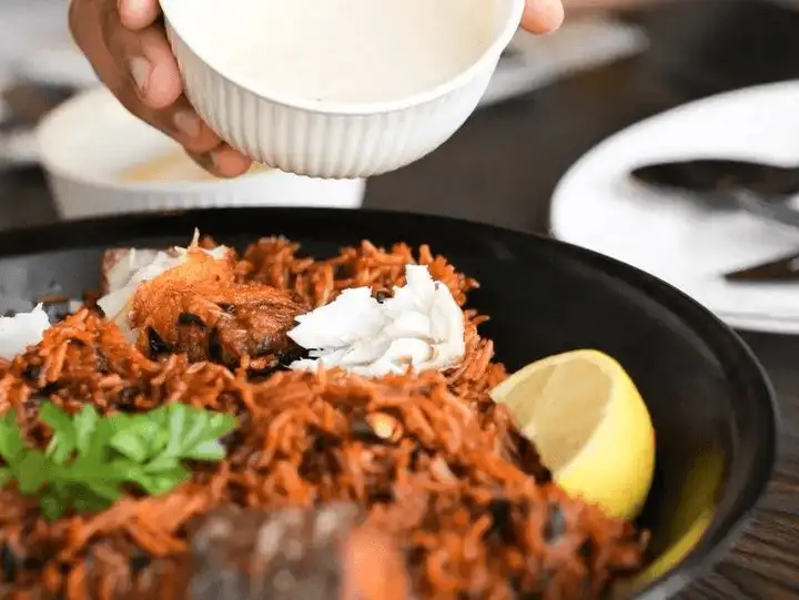 Aromatic biryani with tender chicken, served with yogurt and salad.