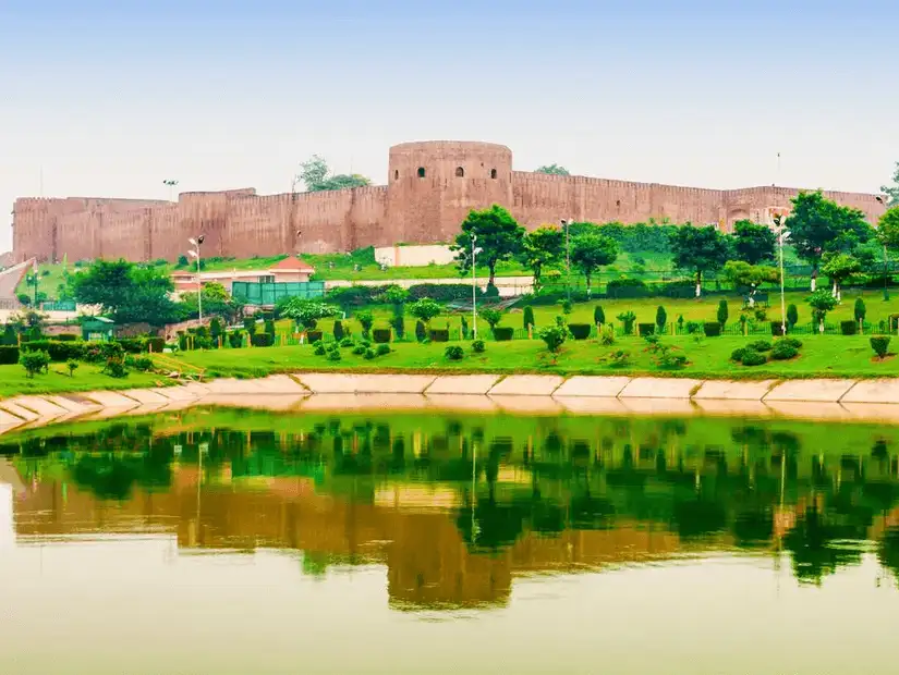A historical fort surrounded by lush greenery and a serene lake.