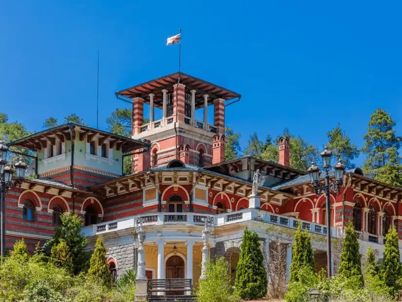 A grand Georgian mansion with intricate architecture and a national flag waving above.