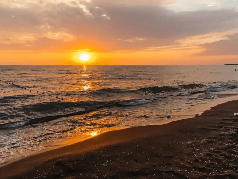 A breathtaking view of a fiery sunset over the tranquil sea waves.