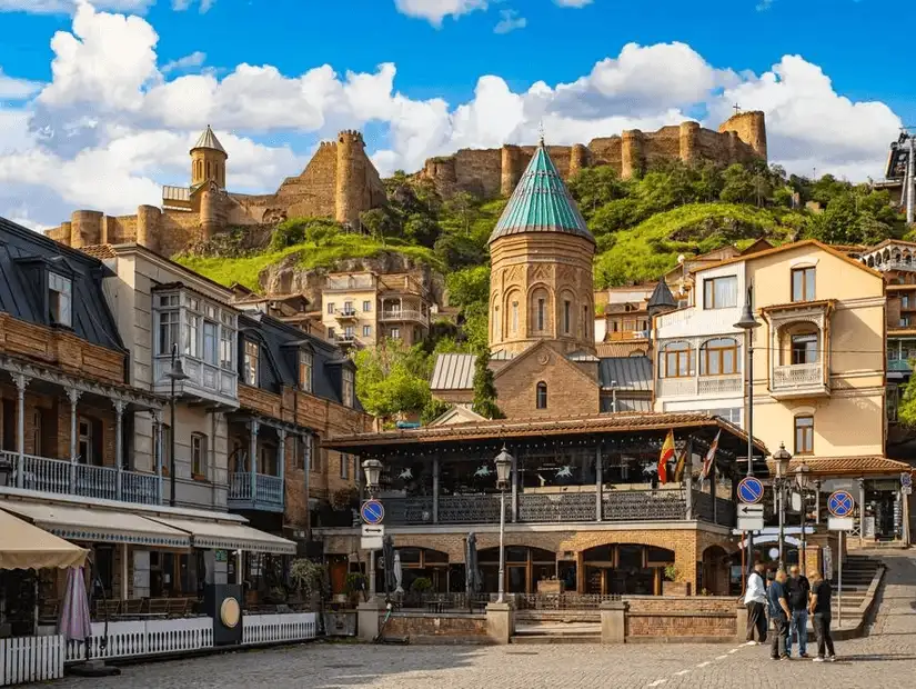 A vibrant city view featuring traditional Georgian architecture and the ancient Narikala Fortress.