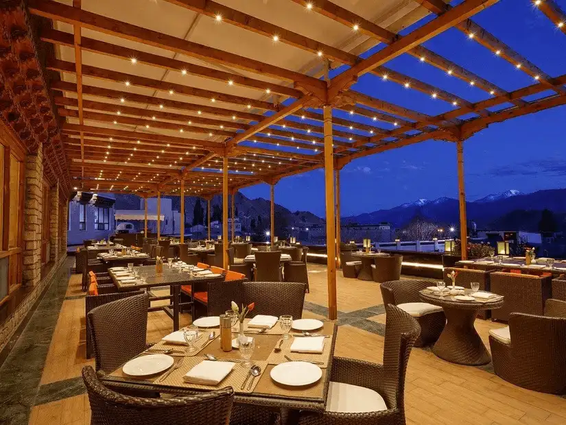 An elegant outdoor restaurant setting with stunning mountain views at night.