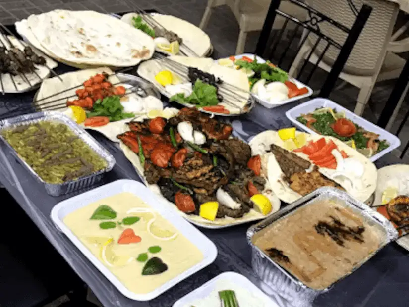 A rich spread of grilled meats, vegetables, and traditional dips served at a Middle Eastern feast, with fresh bread and salads.