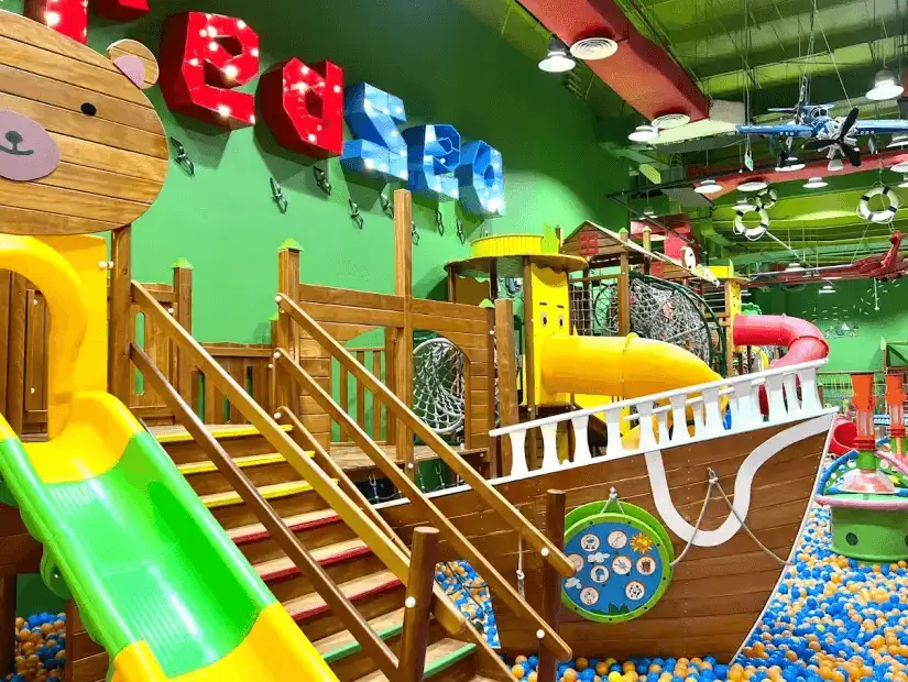 A colorful indoor playground with a pirate ship structure, slide, and ball pit, perfect for children to play and explore.