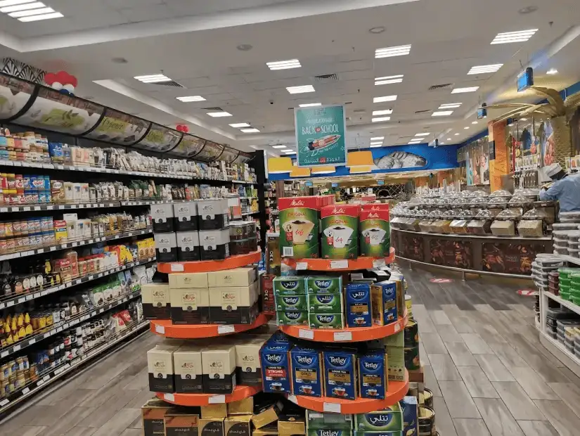 A wide aisle in a grocery store filled with shelves of various products, showcasing a neatly organized shopping area.