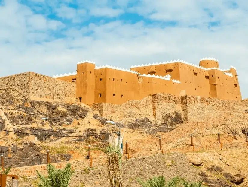 A traditional mud-brick fortress standing tall on a rocky hill under a clear sky.