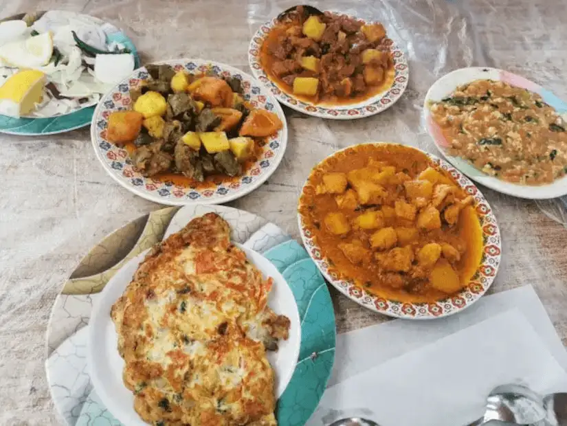 A hearty selection of traditional dishes, including stews, potatoes, and an omelette, served with fresh salad at a local café.