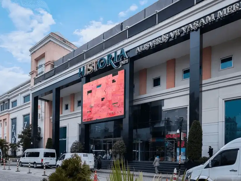 A sleek shopping center, with a digital display, stands in the heart of the city.