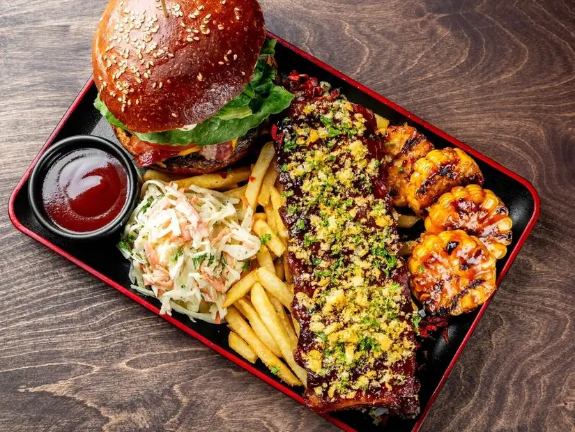 Hearty burger meal with sides of fries, wings, and slaw.