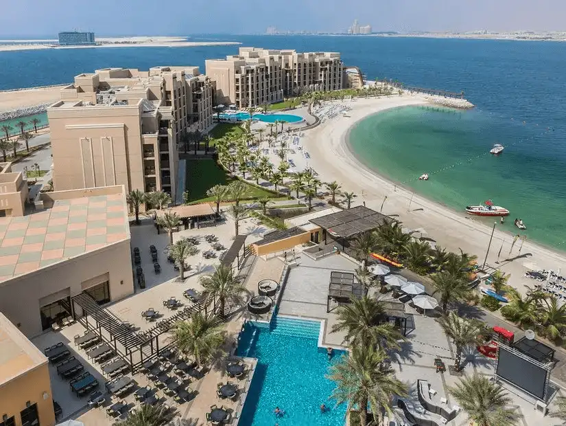 Curving white-sand beach and palm-lined pools fringe a luxury resort complex jutting into the bright blue Arabian Gulf.