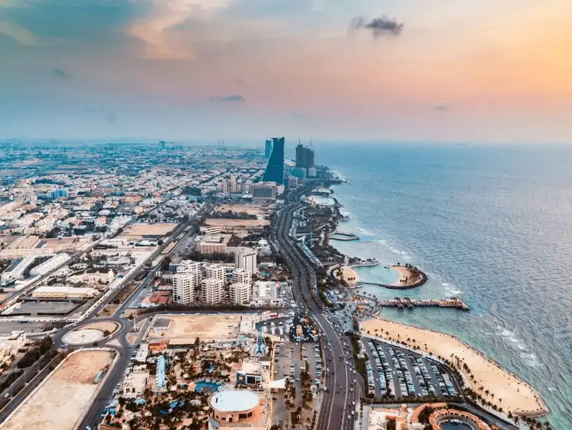 Panoramic aerial view of a coastal cityscape at sunset, highlighting urban and natural harmony.