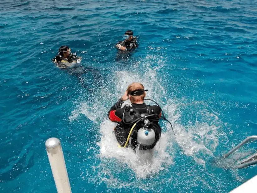 Scuba divers entering the ocean, capturing the dynamic moment of dive initiation.