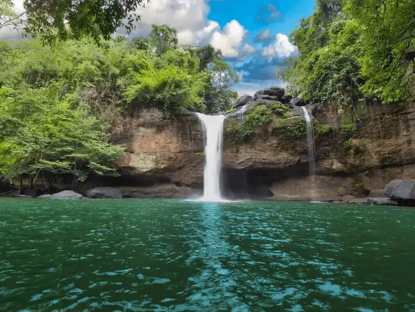 A serene waterfall cascading into a green pool in Khao Yai National Park.