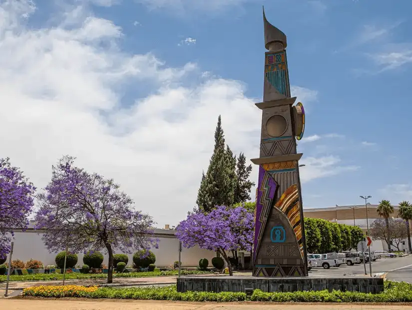 A colorful monument surrounded by vibrant jacaranda trees.