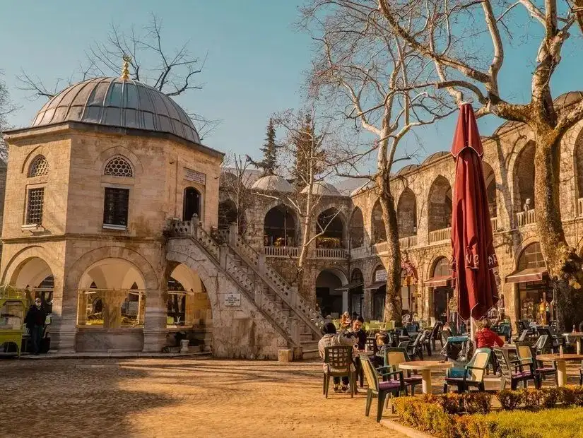 A peaceful view of the Kozahan courtyard, where people enjoy their time in a historic setting.