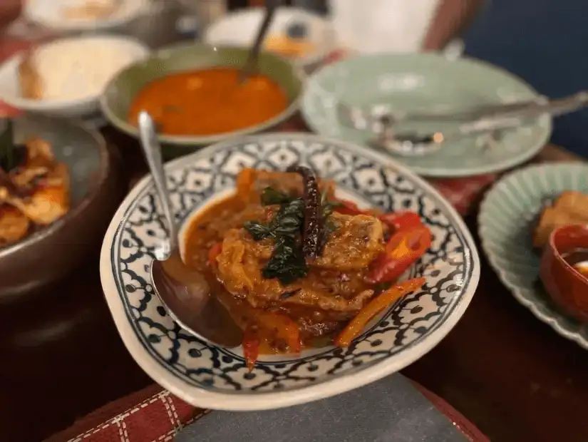 A plate of traditional Thai curry, rich in flavors with vegetables and aromatic spices, served in a cozy restaurant ambiance.