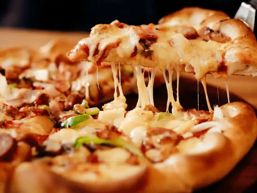 Cheesy pizza topped with an array of meats and vegetables, freshly pulled from the oven.