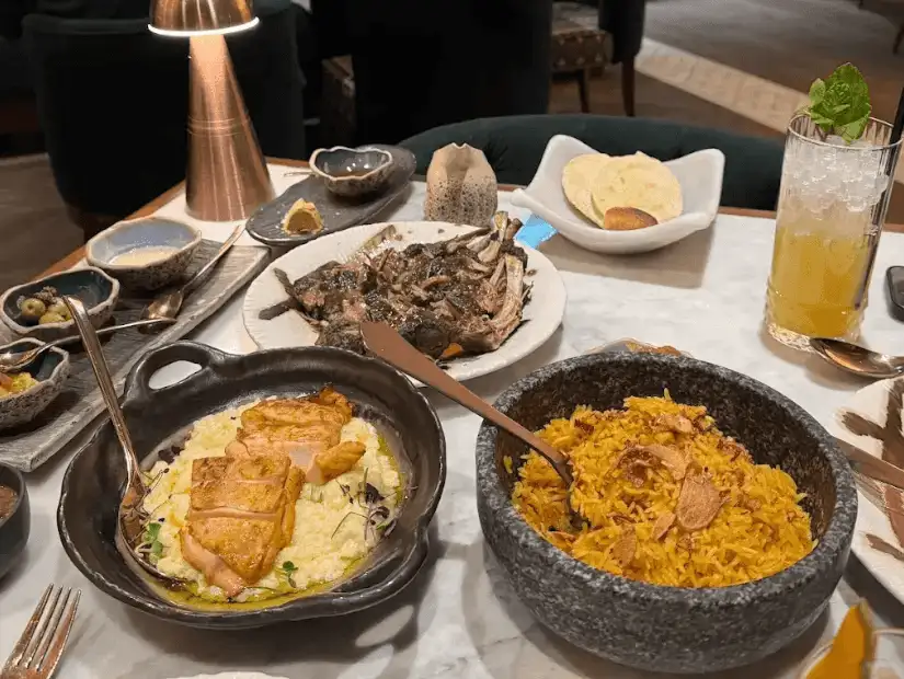 A beautifully plated meal at Maiz Alkhazama, featuring a dish of seasoned grilled meat alongside a side of fluffy rice and vegetables.