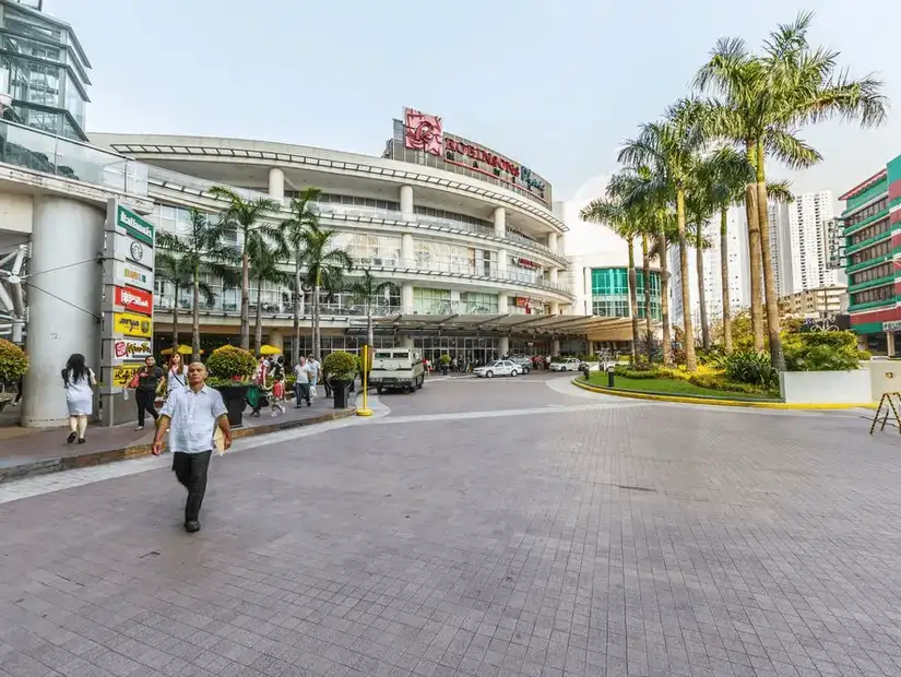 Entrance of a shopping mall with palm trees nearby.