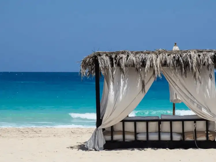 A tranquil beach in Marsa Matruh with clear blue waters and a shaded cabana.