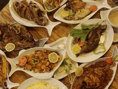 An assortment of grilled seafood dishes beautifully presented on platters with garnishes.