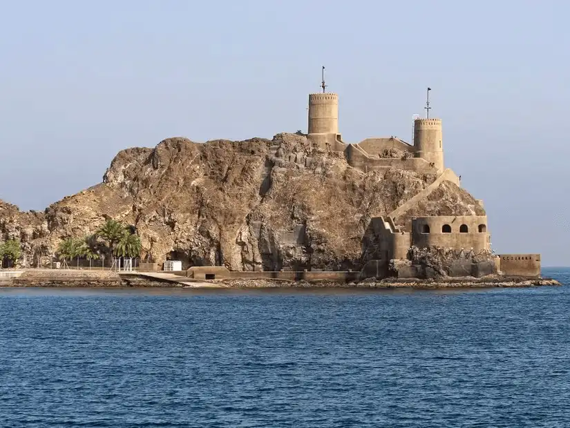 Al Mirani Fort perched on a rocky outcrop overlooking the blue waters, guarding the entrance to Muscat.