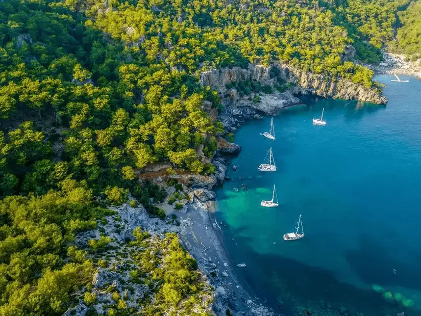 Secluded cove with sailboats nestled along the rugged coastline in Muğla.