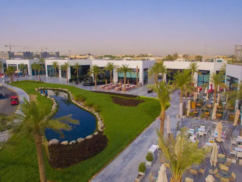 A vibrant outdoor dining area in the Murouj Complex, surrounded by lush greenery and palm trees.