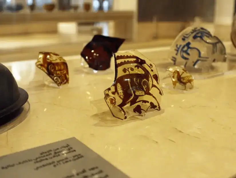 Colorful, ancient glass artifacts displayed at the Museum of Islamic Art, showcasing intricate designs.