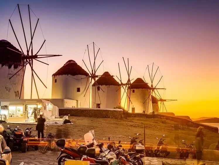 Iconic windmills and vibrant sunsets capture the island’s charm and nightlife spirit.