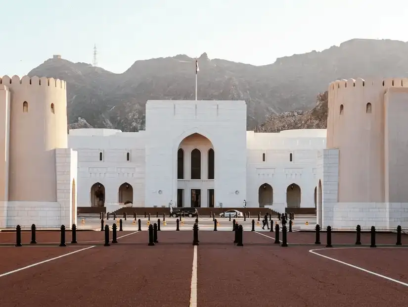 The grand facade of the National Museum of Oman, set against the towering mountains of Muscat.