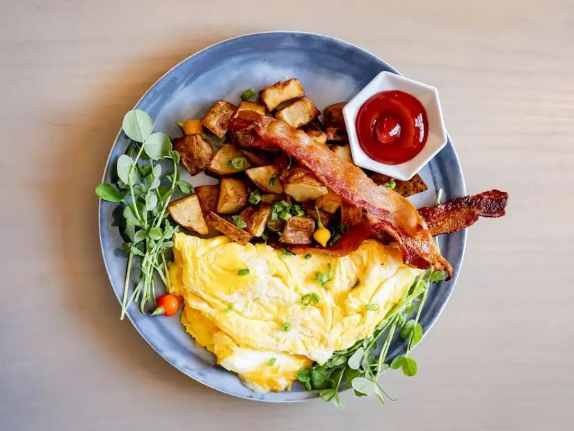 A hearty breakfast plate with bacon, scrambled eggs, and roasted potatoes.