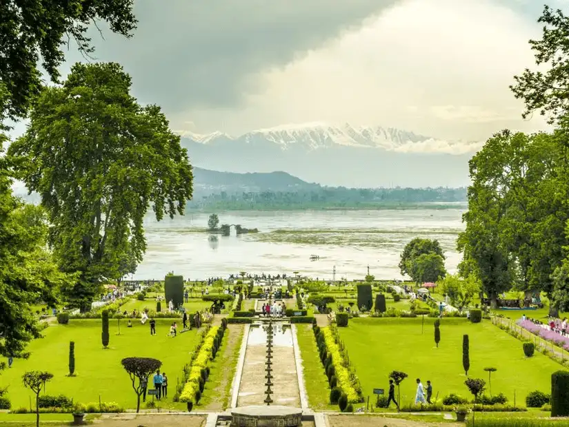 A beautiful view of the well-maintained Nishat Garden with lush greenery and snow-capped mountains in the background.