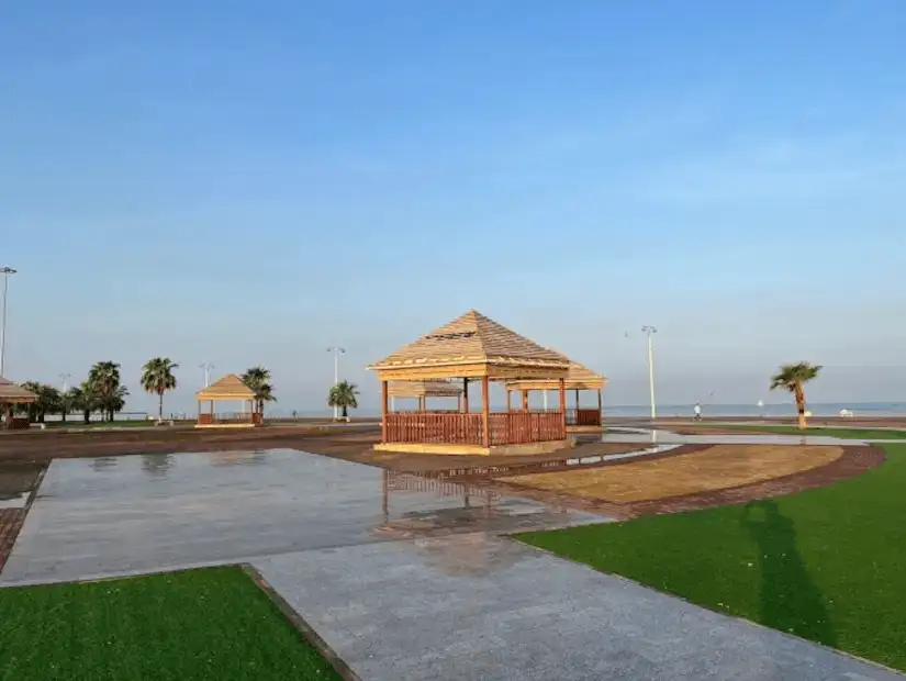 Tranquil seaside park with wooden gazebos and lush greenery.