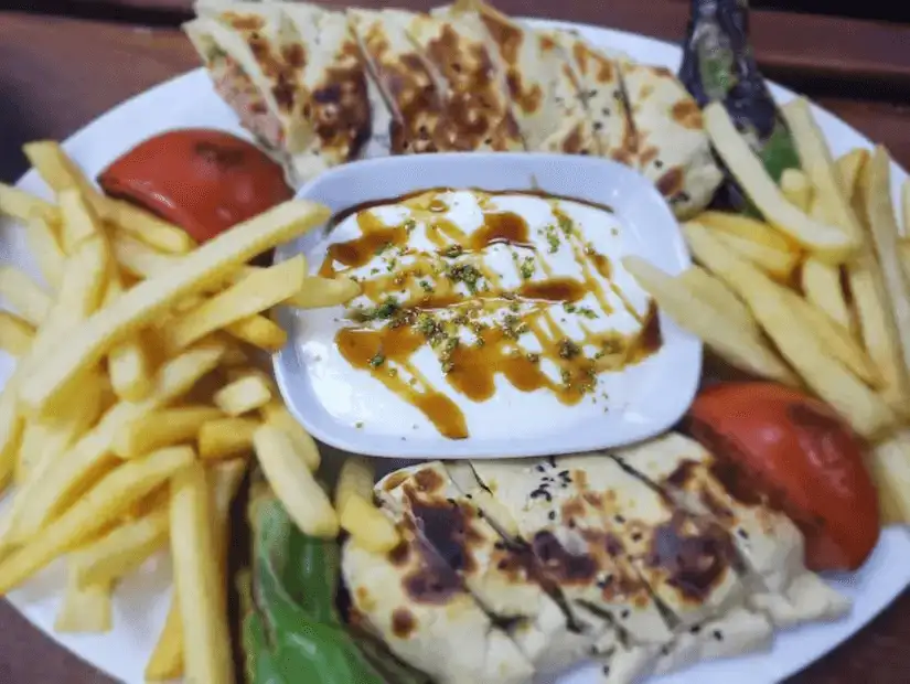 A plate of grilled flatbread, fries, and dipping sauce.