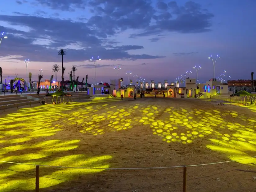 Evening view of a brightly lit outdoor event space with unique lighting patterns. 