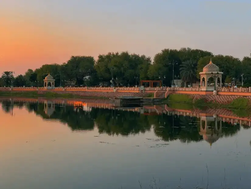 The peaceful setting of the Omani Mangrove Park at sunset, with reflections of pavilions in the calm waters.