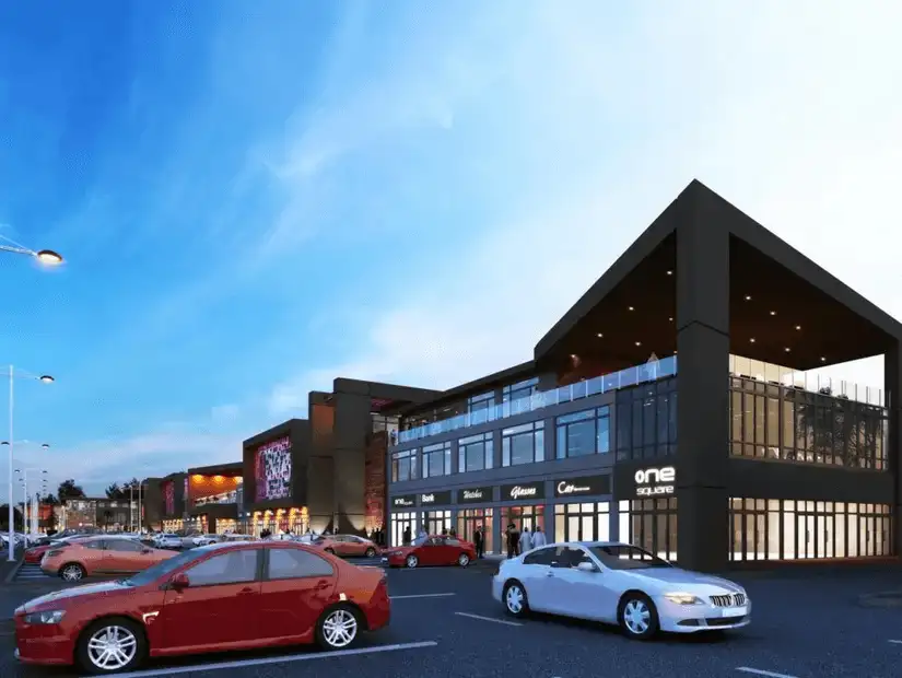 Bustling suburban shopping center, showcasing modern architecture and a busy parking lot under a clear sky.