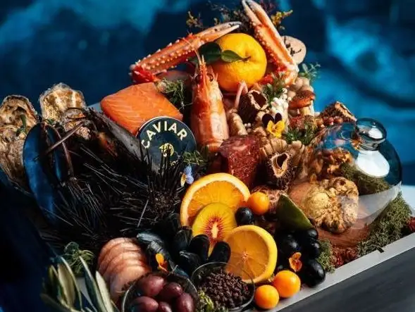 An extravagant assortment of fresh seafood, including salmon, crab, and caviar, artistically presented with vibrant fruits and flowers.