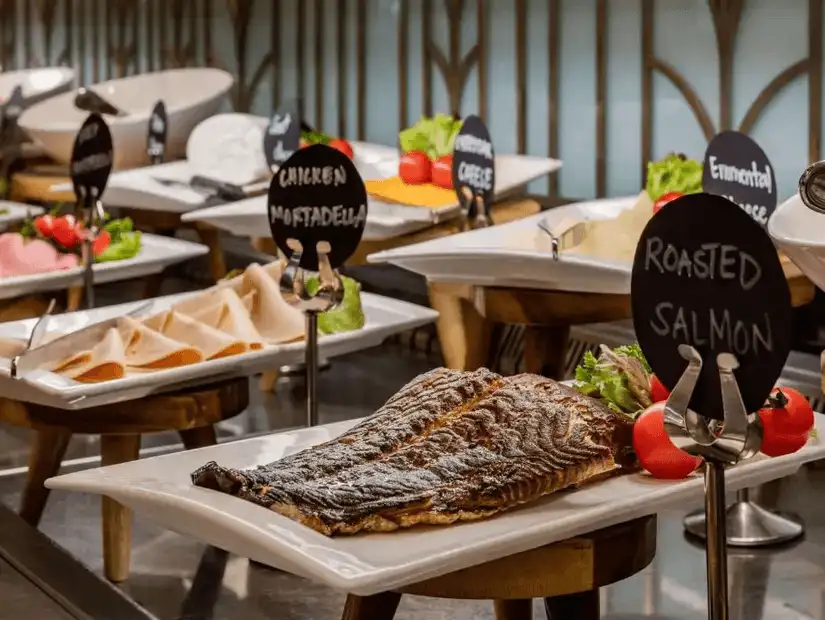 An elegant buffet spread featuring roasted salmon and a variety of meats, beautifully presented with fresh vegetables.