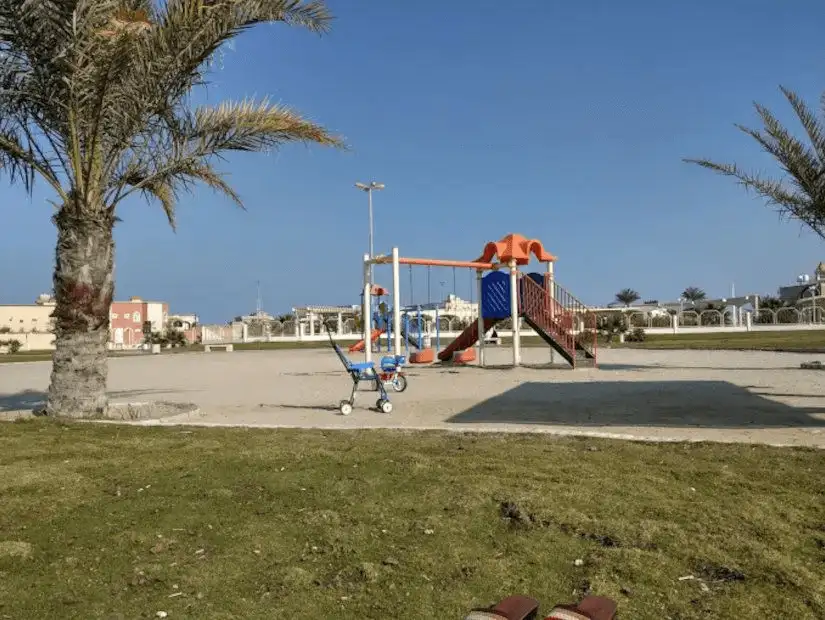 Quiet playground in Khafji with a single tricycle parked beside the swings.