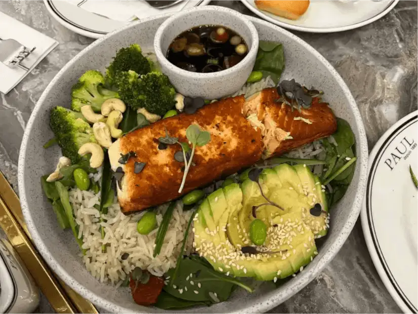 A bowl of rice with grilled salmon and vegetables.