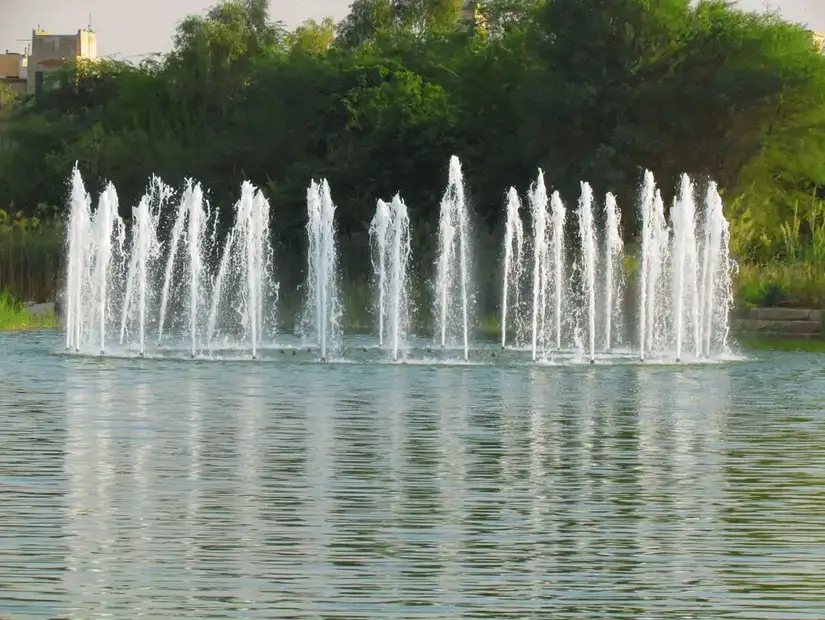 A row of majestic water fountains set against a lush, green backdrop.