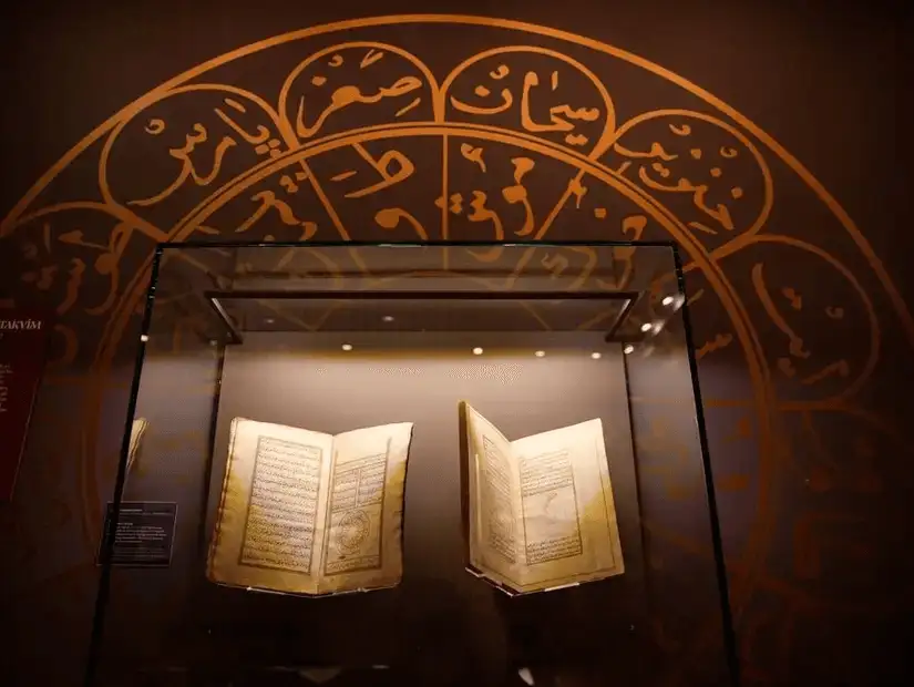 A historical display of rare Islamic manuscripts, beautifully illuminated under soft lighting.