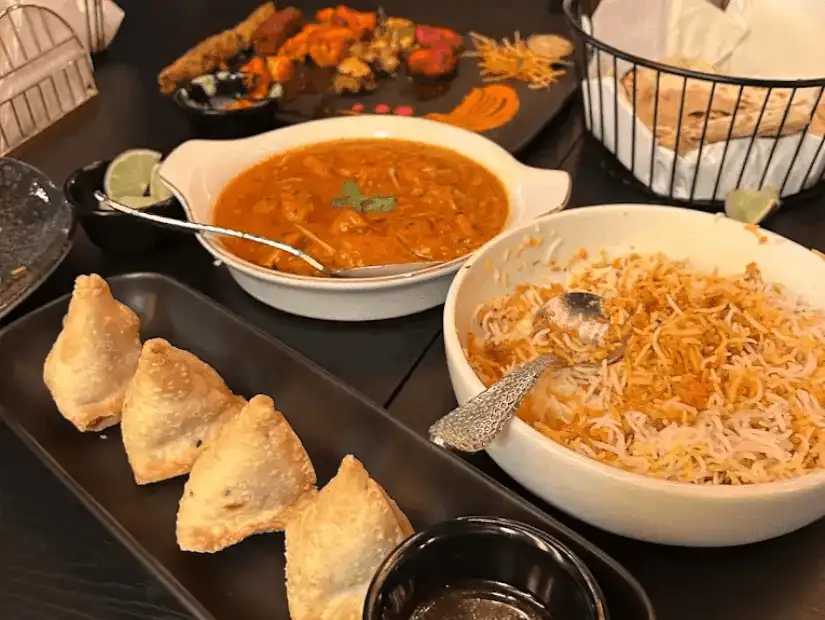 A delicious mix of aromatic rice, curry, and savory accompaniments, served with crispy samosas.