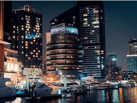 Luxurious yachts and illuminated skyscrapers reflect the vibrant urban lifestyle.