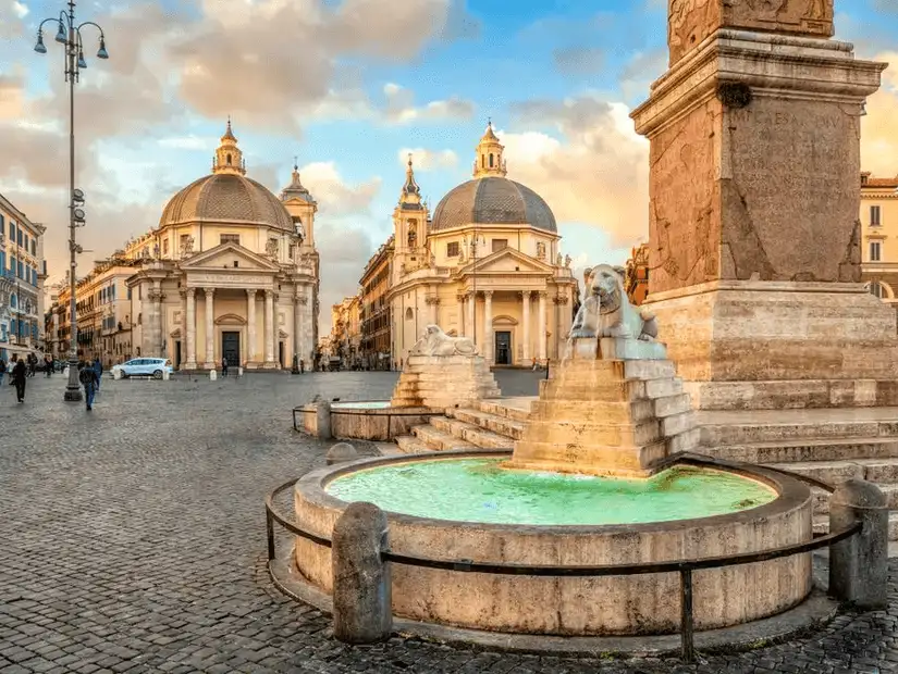 The beautiful Piazza del Popolo, with its fountains and twin churches, under a soft evening light.