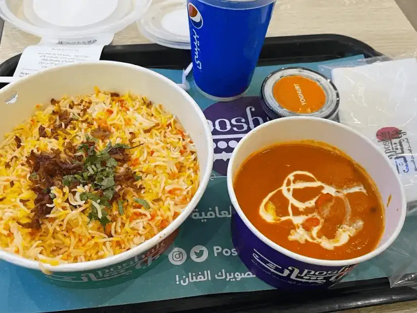 A plate of biryani rice with curry served with a drink.