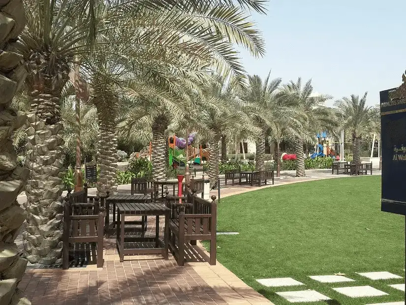 Shady seating areas surrounded by palms at Princess Sabeeka Park, a relaxing green space.